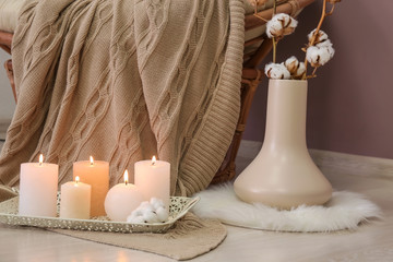 Beautiful burning candles and vase with cotton branches on floor