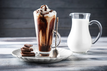 Glass cup of tasty cold coffee with chocolate on wooden table
