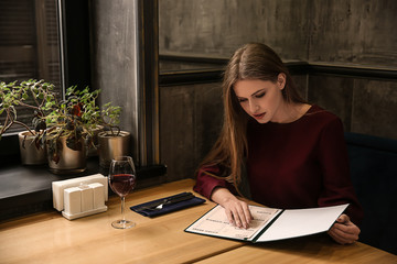 Young woman looking through menu in restaurant