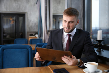 Young man looking through menu in restaurant