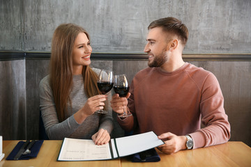 Young couple with menu sitting in restaurant