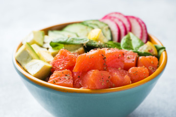 Traditional Hawaiian Poke salad with salmon, avocado rice and vegetables in a bowl.