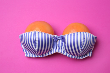 Ripe grapefruits in bra on color background