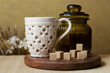 Cubes of brown sugar on the kitchen table. Rustic still life with wooden and glass utensils.