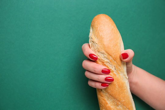 Woman holding fresh baguette on color background. Erotic concept