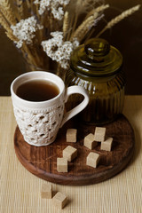 Cubes of brown sugar on the kitchen table. Rustic still life with wooden and glass utensils.