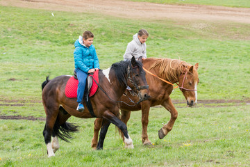 Boy and girl riding horses on the green meadow