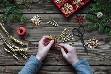 Making of handmade christmas toys from straw with your own hands. Children's DIY concept. Making xmas tree decoration. Step 3. Wrap a contrast thread. - obrazy, fototapety, plakaty