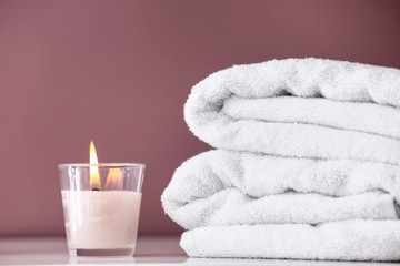 Obraz na płótnie Canvas Clean towels and burning candle on shelf in bathroom