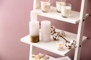 Many burning candles on shelves near color wall