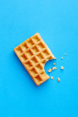 Single fresh waffle isolated on a blue background viewed from above. Top view