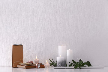 Fototapeta na wymiar Beautiful composition with burning candles on table near white wall