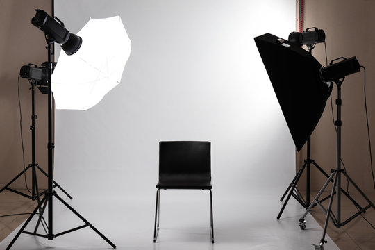 Interior of modern photo studio with professional equipment and chair