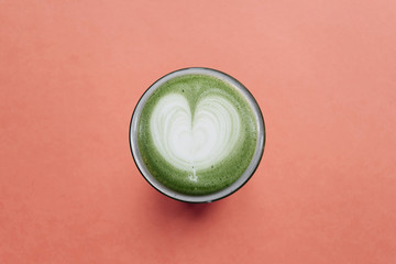 Fresh useful green matcha latte coffee on a red background.