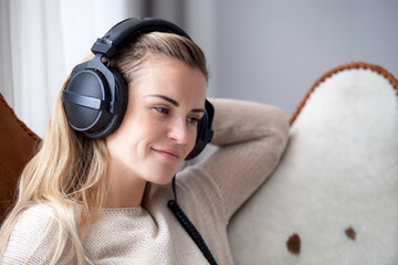 Young woman wearing headphones listening to music and relaxing at home