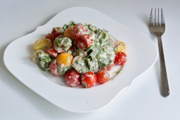 Tasty tomato salad on the white plate with fork.