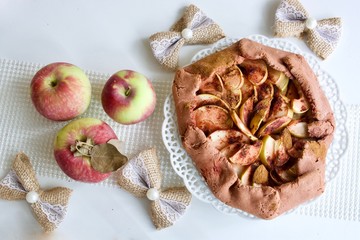 Tasty apple-cinnamon pie with apples on the white table.
