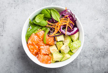Top view of poke bowl with fresh raw salmon, avocado, rice, spinach, vegetables. Traditional...