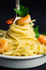 spaghetti with shrimp around a fork on a black background