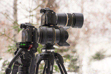 Two cameras on a tripod shoot a report about the weather during a snowfall.