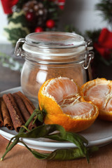 jar of cinnamon, cinnamon sticks and tangerines on the background of the Christmas wreath closeup.
