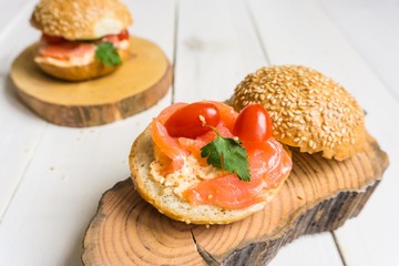 Sandwich with salted salmon, cream cheese, tomato and parsley on wooden plates