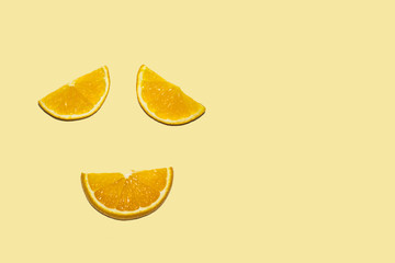three orange slices lie on an orange background on the left in the form of a face satisfied eyes smiling mouth