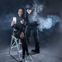 A man smokes an electronic cigarette. A man in the smoke. The guy and the girl smokes an electronic...