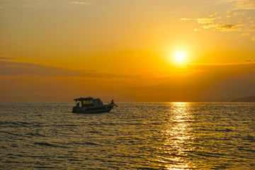 A small yacht in the sea, at a picturesque sunset