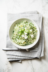 Spinach risotto with a glass of white wine on marble background