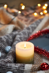 Obraz na płótnie Canvas Candle and Christmas garland on a blanket. Selective focus