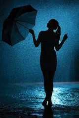 silhouette of the figure of a young girl with an umbrella in the rain, a young woman is happy to drops of water, concept weather and mood