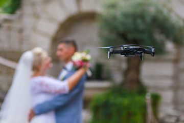 Hovering drone taking pictures of wedding couple in nature - obrazy, fototapety, plakaty
