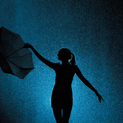 silhouette of the figure of a young girl with an umbrella in the rain, a young woman is happy to drops of water, concept weather and mood