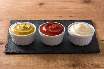 Ketchup,mustard and mayonnaise in a bowls on black slate