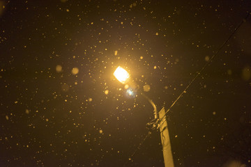 Snow at night on the background of night lighting in winter lantern