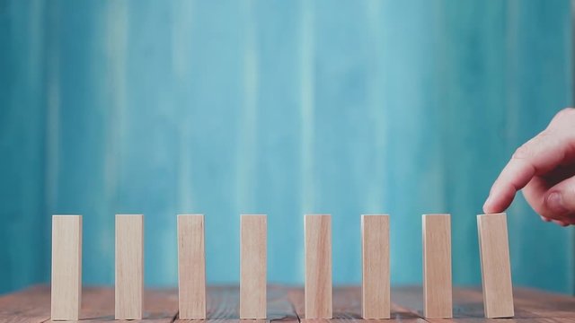 Domino effect. Wooden dominoes falling in sequences, chain reaction on a wooden table.