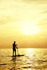 Sunset Silhouette Of Young Handsome Man Paddling On Surfboard Toward The Horizon In The Open Sea Beautiful Scenic Sunset