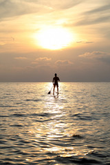 Fototapeta premium Sunset Silhouette Of Young Handsome Man Paddling On Surfboard Toward The Horizon In The Open Sea Beautiful Scenic Sunset