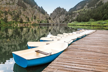 Fototapeta na wymiar Boat rental for tourists on a mountain lake in the valley of Nuria, Spain. Pyrenees ridge.