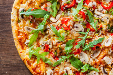 vegetarian Pizza with Mozzarella cheese, mushrooms, tomato sauce, pepper, Spices and Fresh arugula. Italian pizza on wooden table background