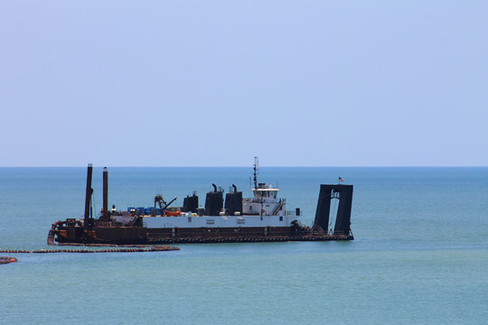 Ship with boom, in the Gulf of Mexico, Madeira Beach, Florida.  Ship is dredging sand from the sea floor. Lots of sky and water in image.