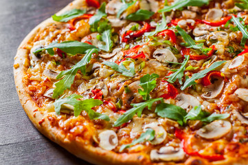 vegetarian Pizza with Mozzarella cheese, mushrooms, tomato sauce, pepper, Spices and Fresh arugula. Italian pizza on wooden table background