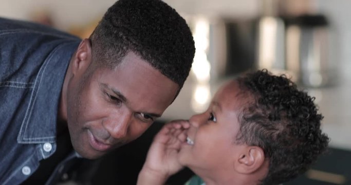 African American boy whispering in fathers ear