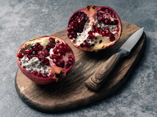 red pomegranate on wooden plate. Gray background.