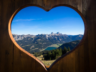 Tannheimer Tal panorama with view on the Haldensee seen through a wooden heart