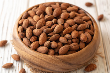 Almonds in bowl on white wooden background. Selective focus.