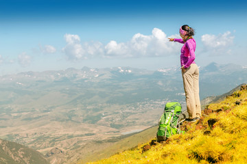 happy woman backpacker and hiker looking at the view with arms outstretched on mountain top