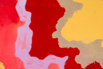 Red, purple, brown and yellow details of abstract paint on a wall.