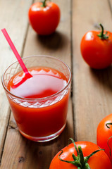 Tomato juice in glass with fresh tomatoes and salt. Rustic wooden background.